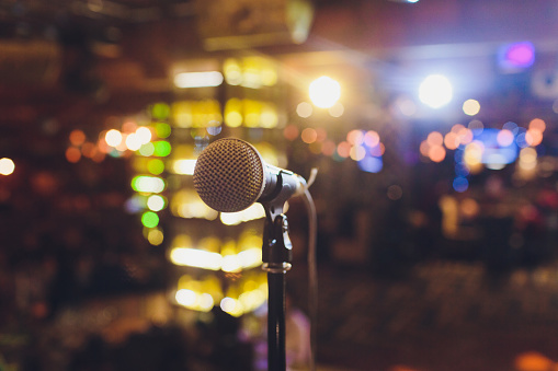 Close up microphone on stage in concert hall restaurant or conference room blurred background
