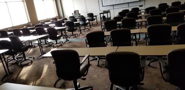 istock Empty classroom with glowing afternoon sunlight coming through window and reflecting off tables 1130812116