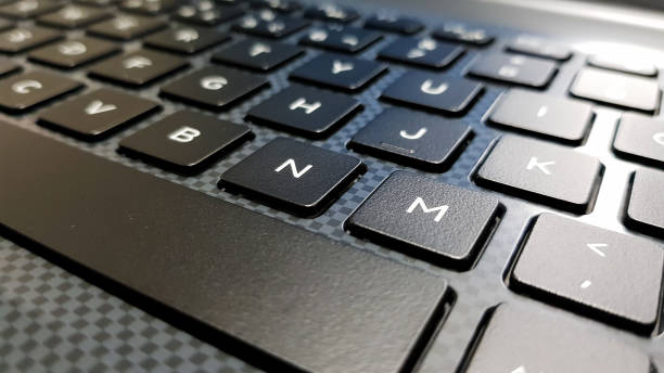 teclado en ángulo lateral centrado en la letra m. keyboard en tonos de gris y negro. - teclado de ordenador fotografías e imágenes de stock