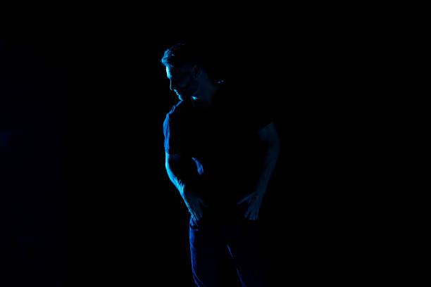 istock Handsome man with black shirt with colored gel lighting 1130817600