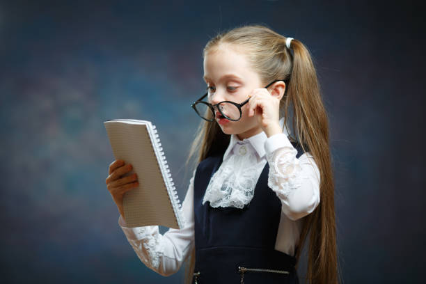 istock Schoolgirl Wear Glasses Uniform Look at Notebook 1130819075