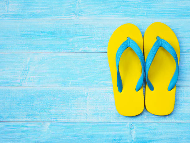 istock yellow rubber flip flop on blue wooden background 1130828346