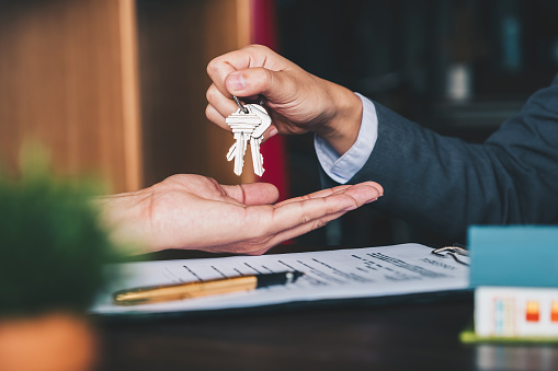 agente inmobiliario dando llaves de la casa a la mujer y firmar acuerdo en la oficina photo