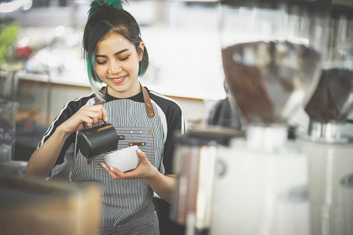 Asiático lindo barista mujer haciendo café en la cafetería photo