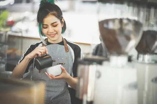 Photo of Asian cute barista woman making coffee in the coffee shop