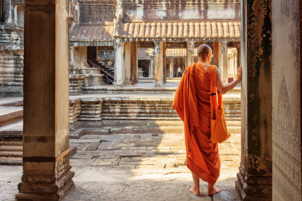 Siem Reap, Cambodia - May 4, 2015: Buddhist monk exploring ancient courtyards of temple complex Angkor Wat in Siem Reap, Cambodia. Mysterious Angkor Wat is a popular destination of tourists and pilgrims.
