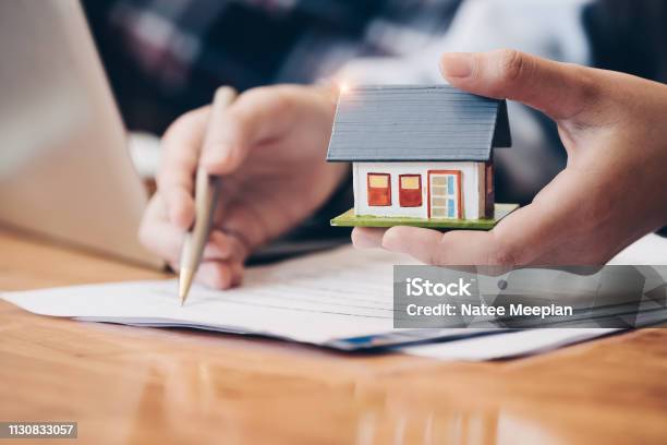 Close Up Real Estate Agent With House Model Hand Putting Signing Contracthave A Contract In Place To Protect Itsigning Of Modest Agreements Form In Officeconcept Real Estatemoving Home Or Renting Property Stock Photo - Download Image Now