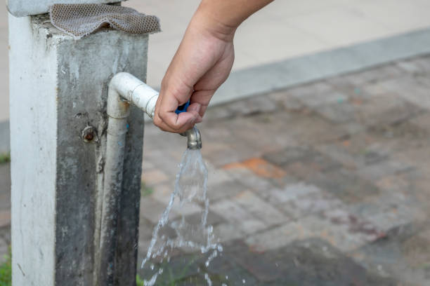 istock Old faucet and hand are open water. 1130834066
