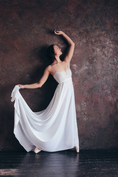 istock Ballet dancer ballerina in beautiful thin flying white dress is posing in dark loft studio 1130837176