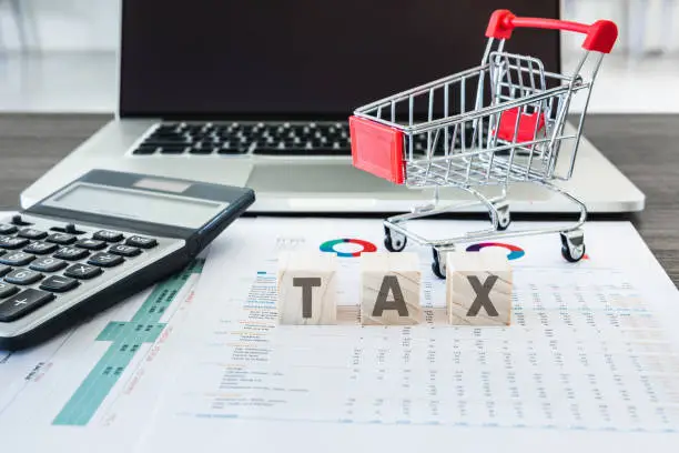 Photo of Business E-Commerce Online and Financial Tax Accounting Concept., Calculator and Mini Cart on Data Fact Sheet in Front of Personal Computer Laptop Background., Customer shopping and E-Payment Concept.