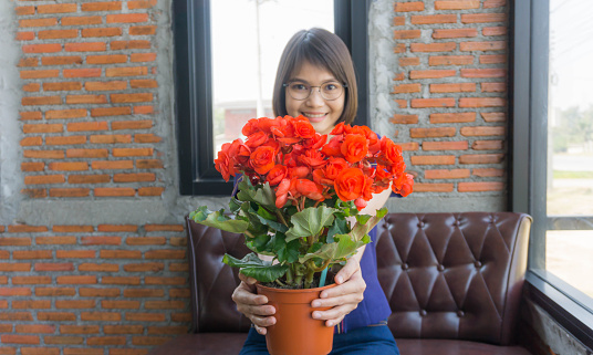 A beautiful woman with a bouquet of red flowers in her hand for a special person.