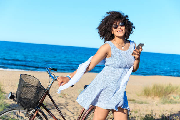 istock African woman with bicycle usung smart phone on the beach 1130852811