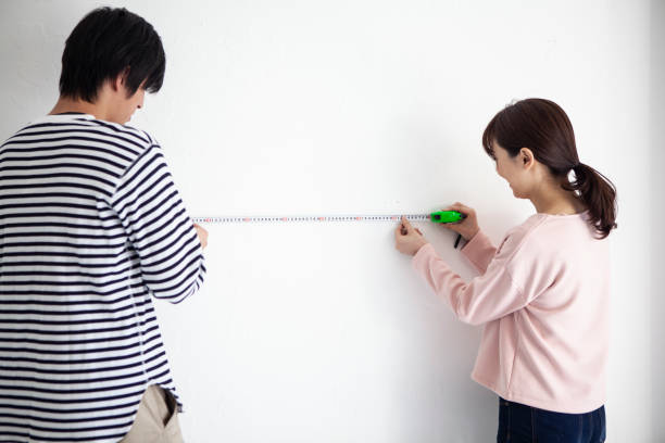 A couple measuring the walls of a new house A couple measuring the walls of a new house measuring a room stock pictures, royalty-free photos & images