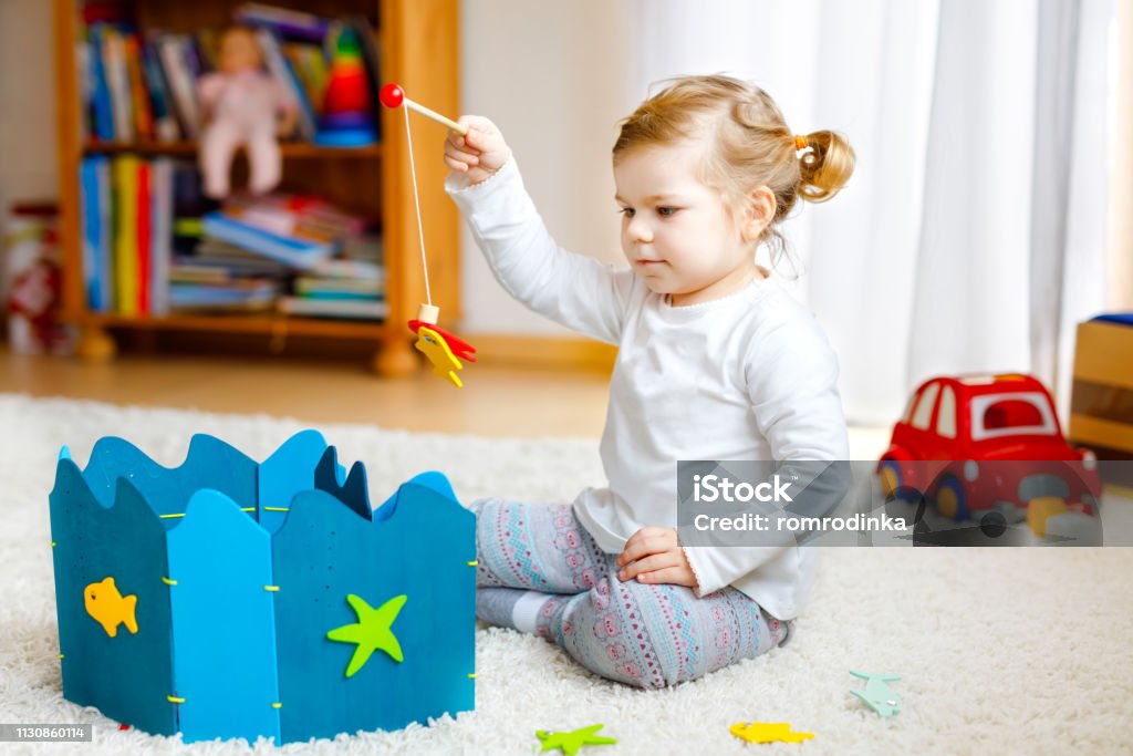 Adorable Cute Toddler Girl Playing With Wooden Fishing Game At Home Or  Nursery Happy Healthy Child Training Memory Grabbing With Fishing Rod  Development And Coordination Step And Education Of Kid Stock Photo 
