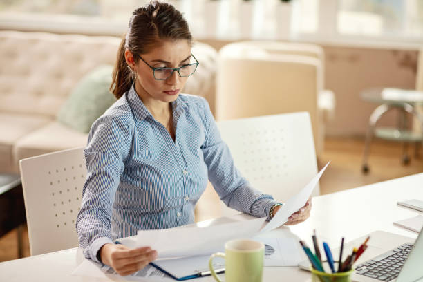 istock Young serious businesswoman going through paperwork in the office. 1130861637