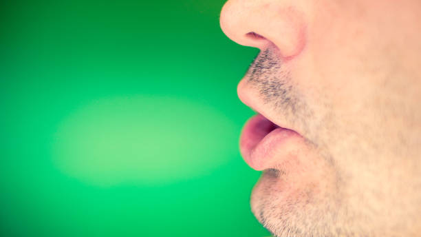 Man's mouth. Man's lower part of face. Emotional series. Studio shot. Green background. human mouth stock pictures, royalty-free photos & images