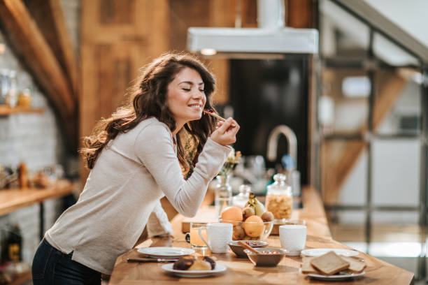 istock Happy woman enjoying while eating marmalade in the kitchen. 1130863513