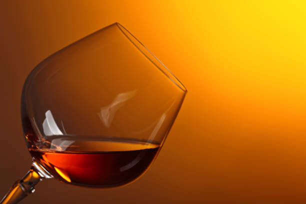 Snifter of brandy with copy space for text on a yellow background.