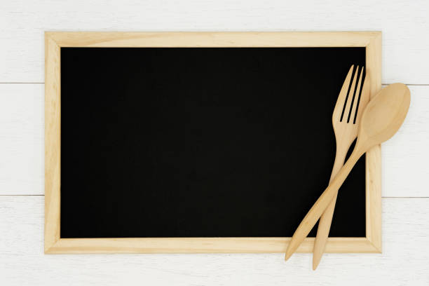 istock Blank chalkboard with wooden spoon and fork on white wood plank background. 1130867305