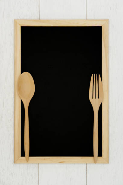 istock Blank chalkboard with wooden spoon and fork on white wood plank background. 1130869688