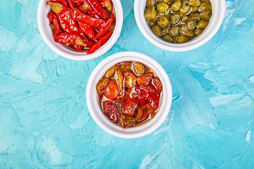 Italian preserved set - marinated capers and pepper, Sundried tomatoes in white bowls. Mediterranean. Copy space.