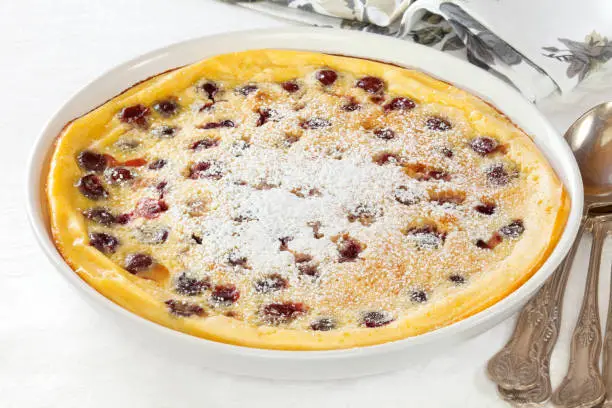 Popular French dessert Cherry Clafoutis, a baked batter pudding with morello cherries, sprinkled with icing sugar.