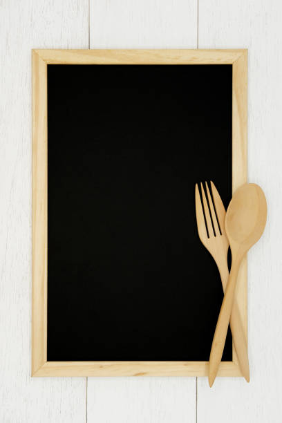 istock Blank chalkboard with wooden spoon and fork on white wood plank background. 1130876593
