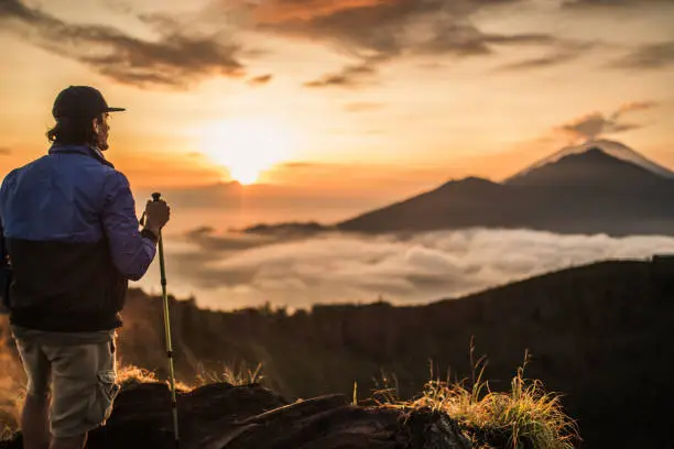 One man, standing high on beautiful mountain Batur in sunset alone.