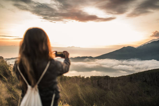 istock Woman photographing sunset 1130878930