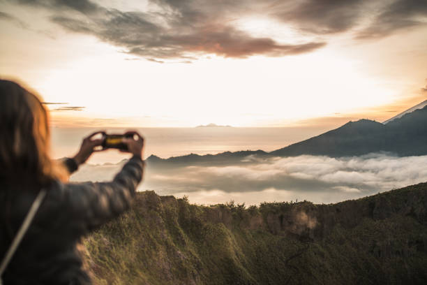 istock Lady photographing sunset with phone on mountain 1130879159