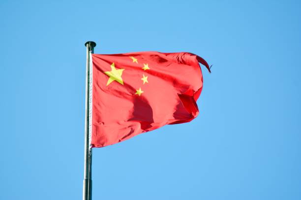 istock Chinese flag with flag pole waving in the wind over blue sky background 1130880634