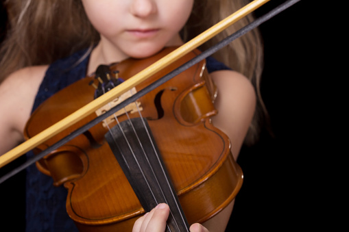 Violin closeup of girl playing the violin isolated on black background