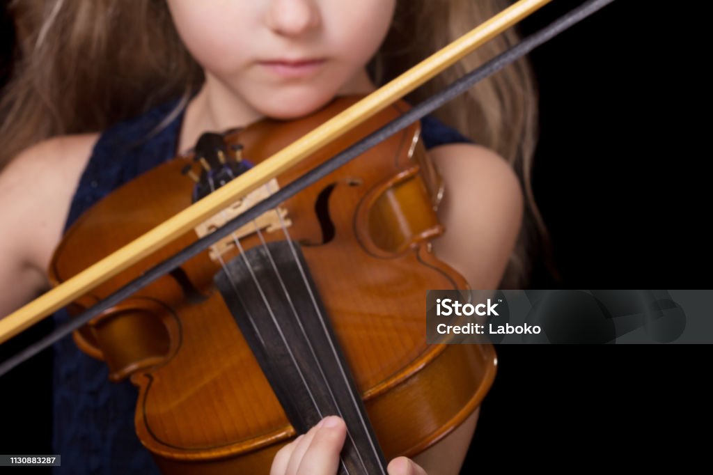 Violin closeup of girl playing the violin isolated on black background Violin closeup of girl playing the violin isolated on a black background Child Stock Photo