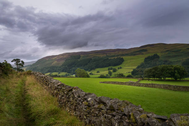 istock Dark clouds over green countryside hill landscape England 1130888097