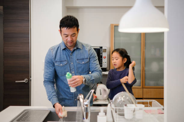 istock Father and daughter washing dishes in kitchen 1130888219