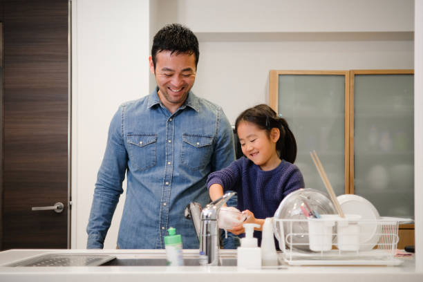 istock Father and daughter washing dishes in kitchen 1130888252