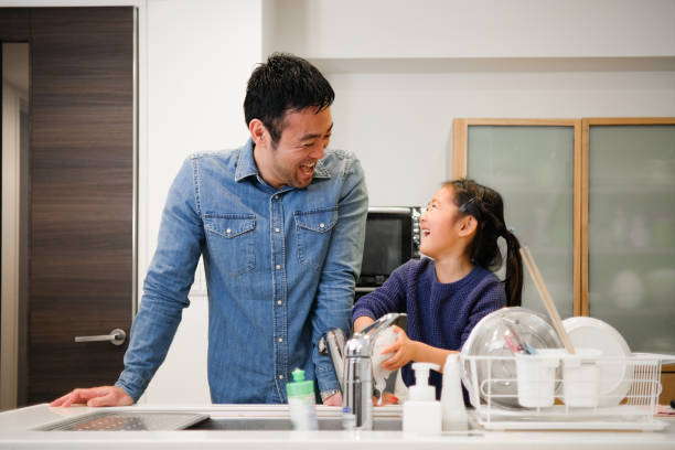 istock Father and daughter washing dishes in kitchen 1130888806