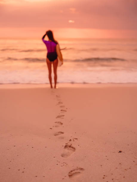 istock Surfer woman with surfboard on a beach at sunset 1130891134