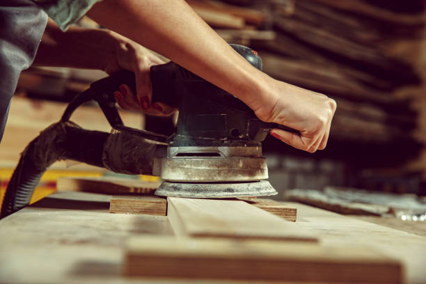 istock Hands of craftswoman grinding timbers with special machine. 1130892426
