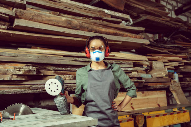 istock Busy and serious craftswoman grinding timbers with special machine. 1130892436