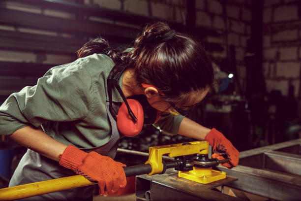 istock Busy and serious craftswoman grinding timbers with special machine. 1130892450