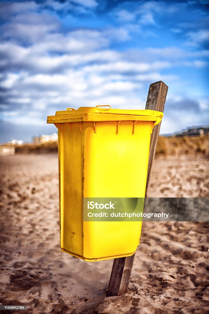 Yellow waste container on the beach Gele afvalcontainer op het strand Beach Stock Photo