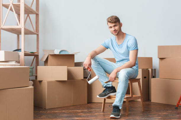 istock Young man moving to new place sitting holding paint roller looking camera joyful 1130896218