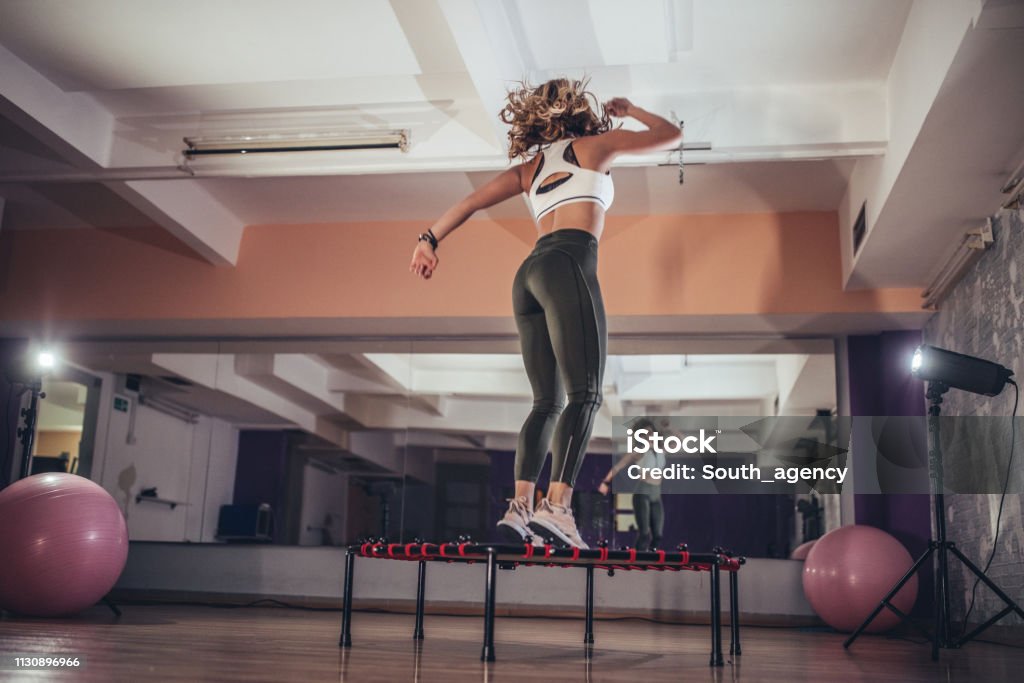 Mujer saltando en mini trampolín - Foto de stock de Trampolín - Artículos deportivos libre de derechos