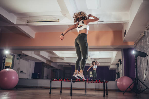 mujer saltando en mini trampolín - trampolín artículos deportivos fotografías e imágenes de stock