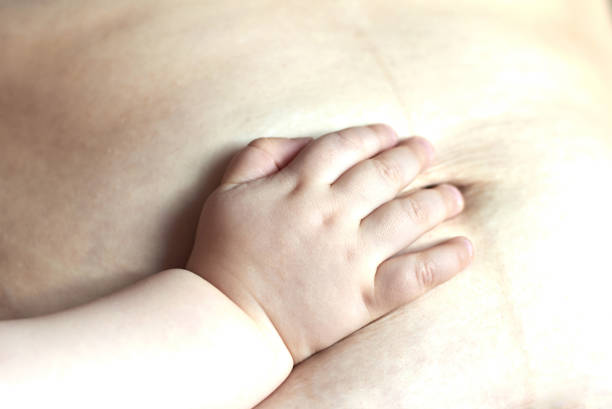 baby touches mom's belly after several months after delivery - loose weight imagens e fotografias de stock