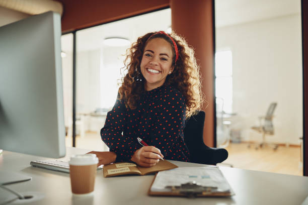 istock Smiling businesswoman writing down notes while working at her desk 1130906401