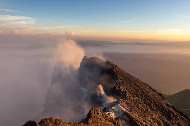 istock Merapi volcano crater rim with people climbing up the summit at sunrise. 1130907640