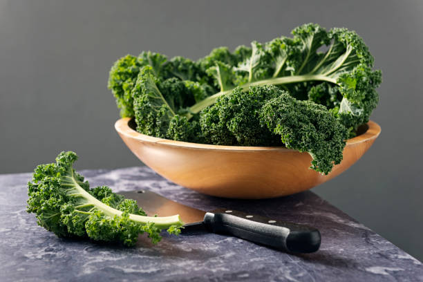 istock Bowl of fresh Kale leaves on a marble table top with a dark background. 1130909921
