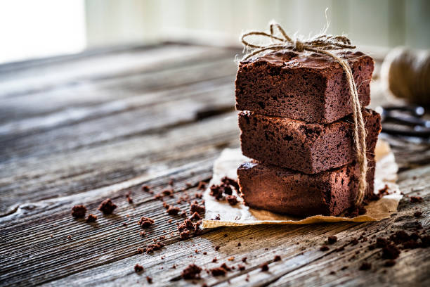 Stack of chocolate brownies on a white plate with purple background. High view.